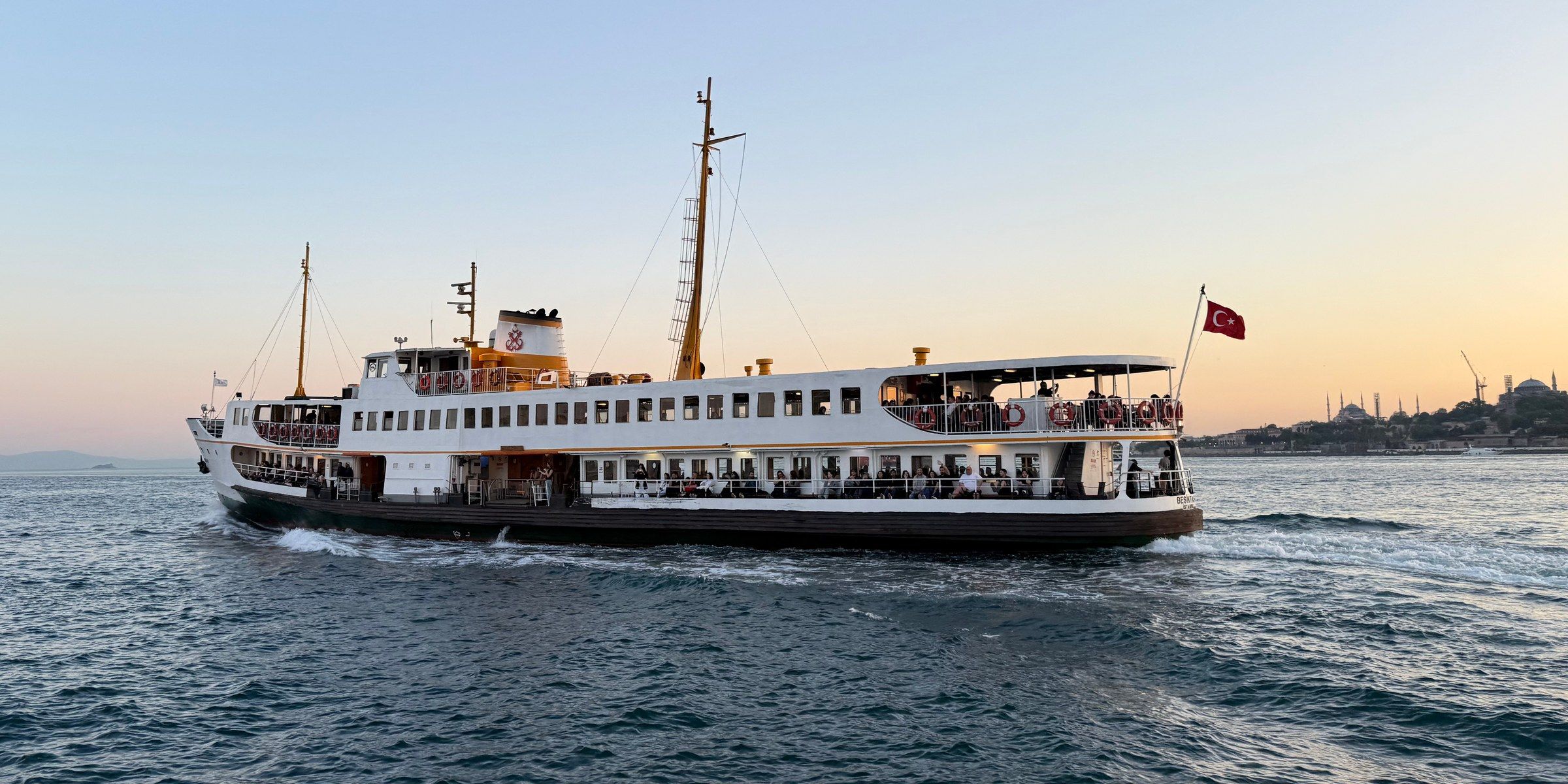 White Şehir Hatları ferry crossing the Bosphorus at golden hour, the Sultanahmet skyline behind it
