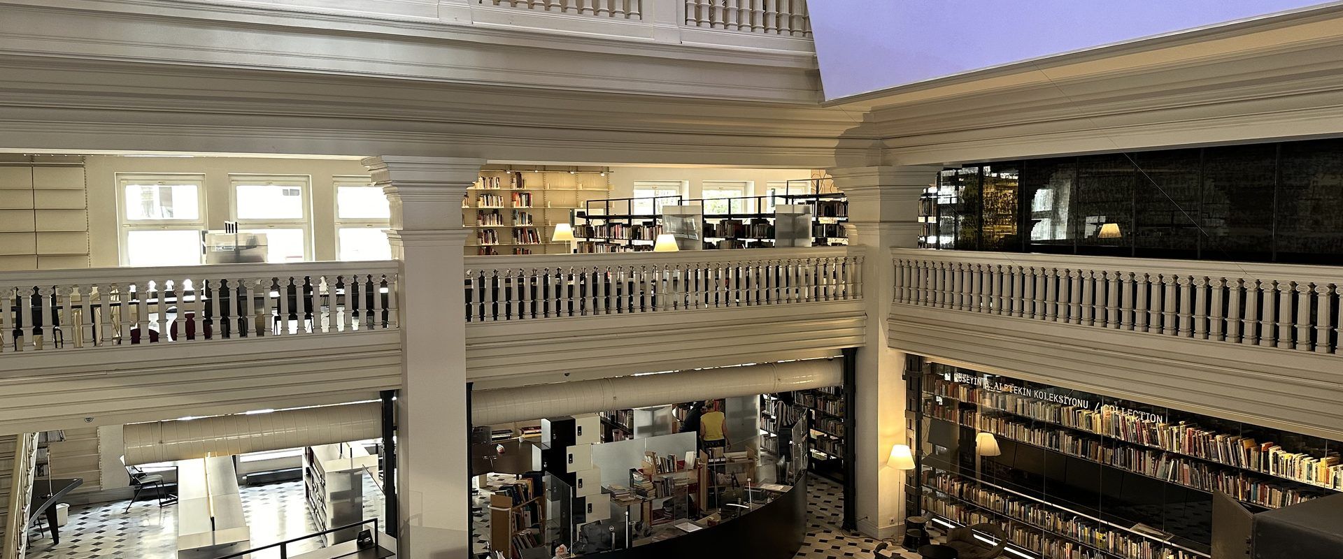Galleried reading hall of a historic Istanbul library, shelves of books below