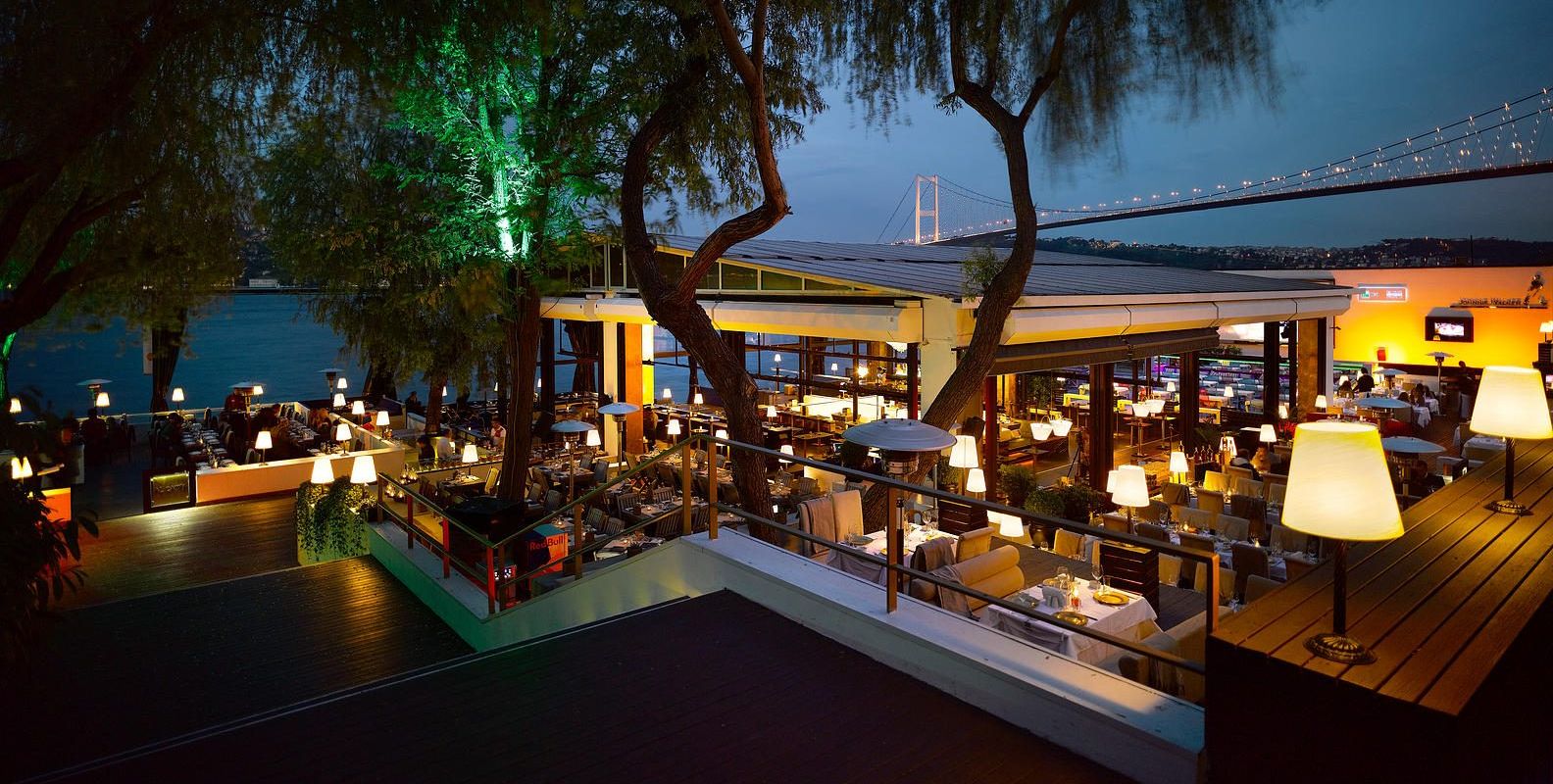 Sortie's waterfront terrace at dusk, the Bosphorus Bridge lit behind, Istanbul